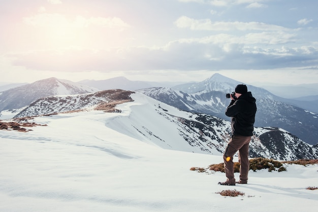 Turista olha a paisagem. Fotógrafo no topo da montanha