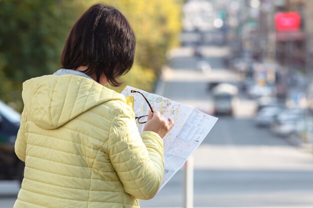 Turista, olhando para o mapa de papel em vez de telefone. Emoção positiva.