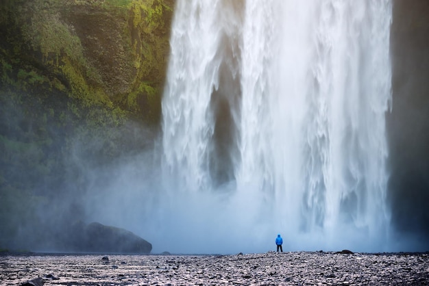 Turista perto da cachoeira skogafoss na islândia