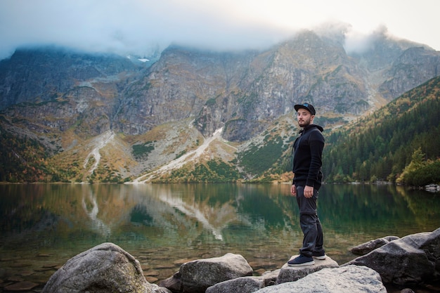 Turista perto do Lago de montanha Morskie Oko no Parque Nacional Tatra, Polônia. Homem feliz caminhante no pitoresco lago nas montanhas no outono.