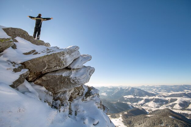 Foto turista de pie en la cima de una montaña nevada
