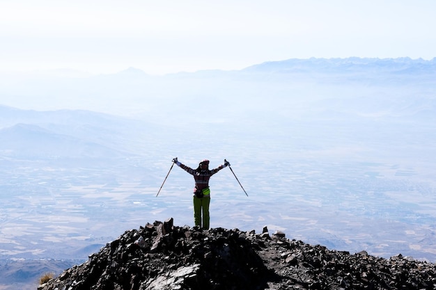 Turista de pie en la cima de la montaña volcánica con las manos levantadas