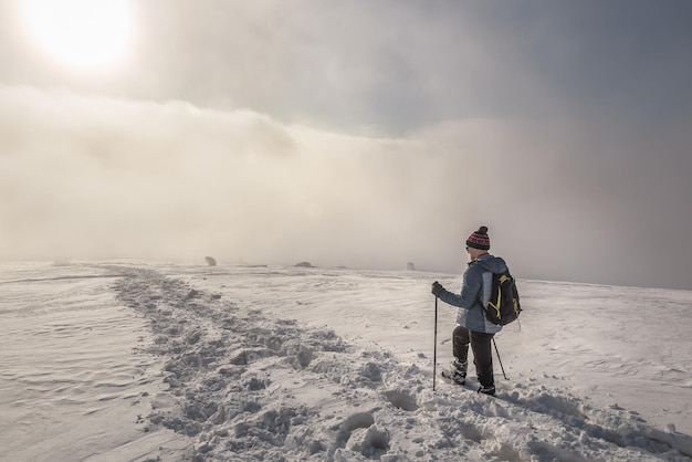 Turista a pie en la niebla en las montañas de invierno