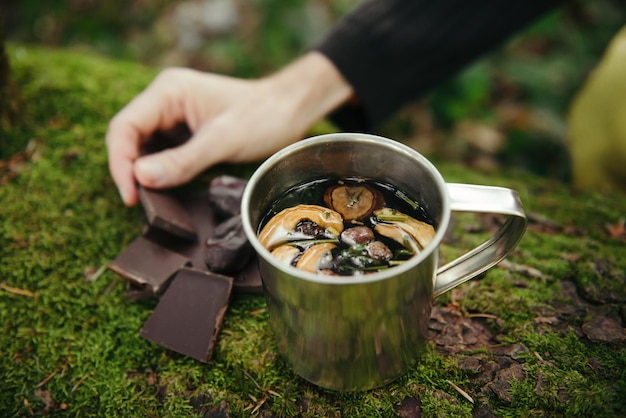 Turista preparando chá de ervas com chocolate durante a caminhada