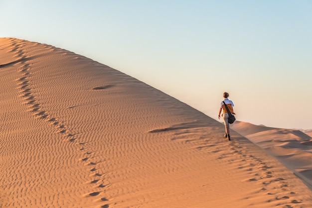 Turista que anda nas dunas de areia em sossusvlei, deserto de namib, parque nacional de namib naukluft, namíbia.