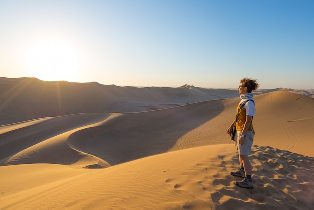 Turista que se coloca en las dunas de arena y que mira la visión en Sossusvlei, desierto de Namib, destino del viaje en Namibia, África.