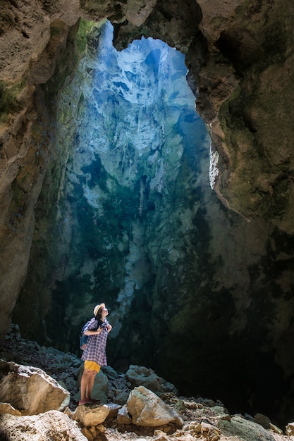 Turista que mira a la luz del sol brillante en la cueva