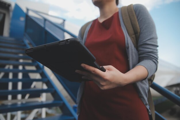 Una turista rubia chequeando la notificación entrante en su teléfono inteligente sentada en el asiento del avión con un netbook Una joven mujer de negocios comparte medios desde el teléfono a la computadora portátil durante el vuelo en avión