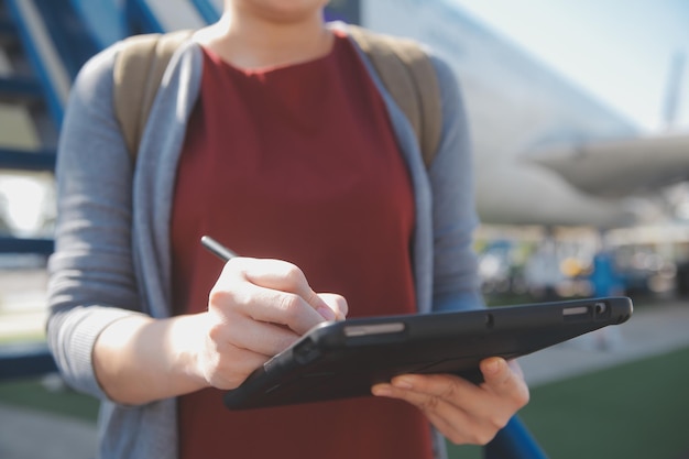 Una turista rubia chequeando la notificación entrante en su teléfono inteligente sentada en el asiento del avión con un netbook Una joven mujer de negocios comparte medios desde el teléfono a la computadora portátil durante el vuelo en avión