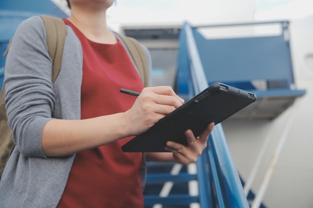 Una turista rubia chequeando la notificación entrante en su teléfono inteligente sentada en el asiento del avión con un netbook Una joven mujer de negocios comparte medios desde el teléfono a la computadora portátil durante el vuelo en avión