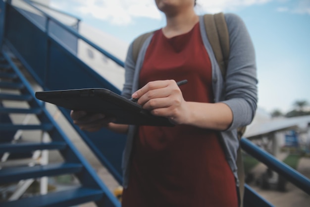 Una turista rubia chequeando la notificación entrante en su teléfono inteligente sentada en el asiento del avión con un netbook Una joven mujer de negocios comparte medios desde el teléfono a la computadora portátil durante el vuelo en avión