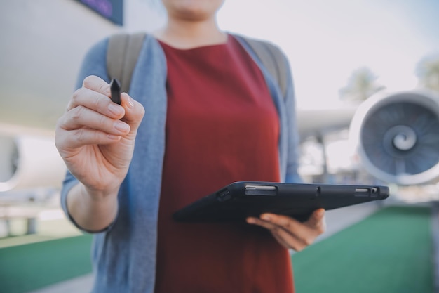 Turista rubia chequeando la notificación entrante en el teléfono inteligente sentada en el asiento del avión con un netbookJoven mujer de negocios comparte medios desde el teléfono en la computadora portátil durante el vuelo en avión