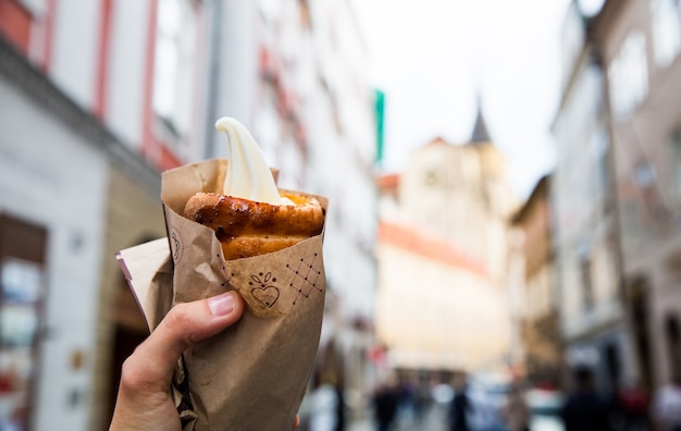 Turista segura Trdelnik no fundo das ruas turísticas da cidade de Praga Tcheca