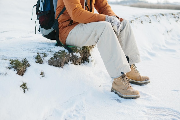 Turista senta e descansa enquanto escala montanhas de inverno