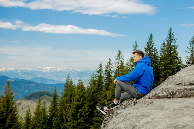 turista senta-se no penhasco e olha para longe. Sente-se. Maravilhosa paisagem montanhosa. Verão é hora