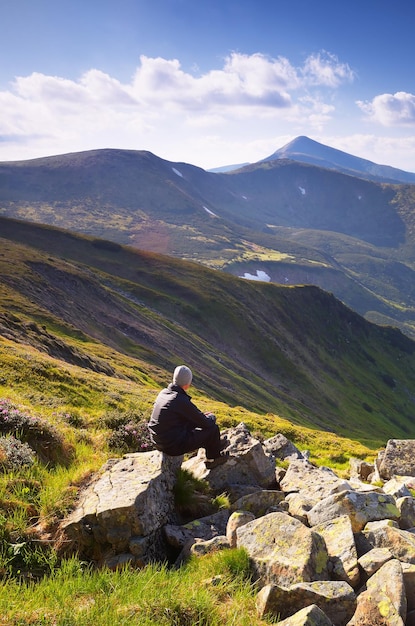 Turista sentada em uma rocha nas montanhas em um dia ensolarado