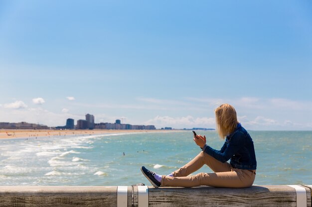 Turista sentado en el muelle, la playa de la ciudad, Europa