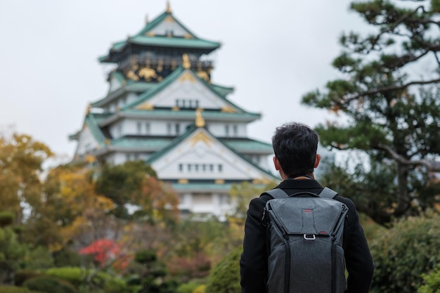 Turista solo viajando no castelo de osaka na temporada de outono visita de viajante asiático na cidade de osaka japão destino de férias e conceito de viagem