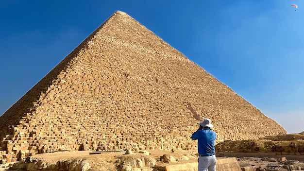 Turista con un sombrero fotografiando una pirámide en Egipto