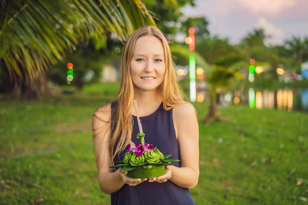 Una turista sostiene el loy krathong en sus manos y está a punto de lanzarlo al agua loy