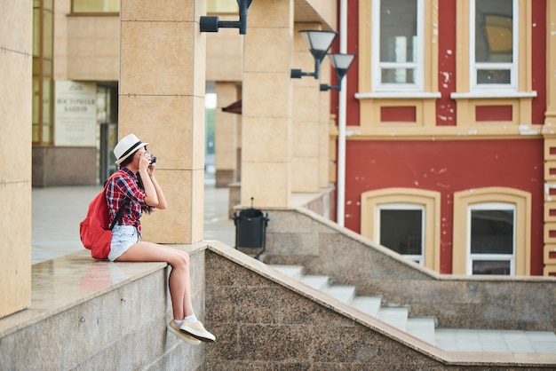 Foto turista tirando fotos da paisagem urbana, sentada em uma superfície de mármore
