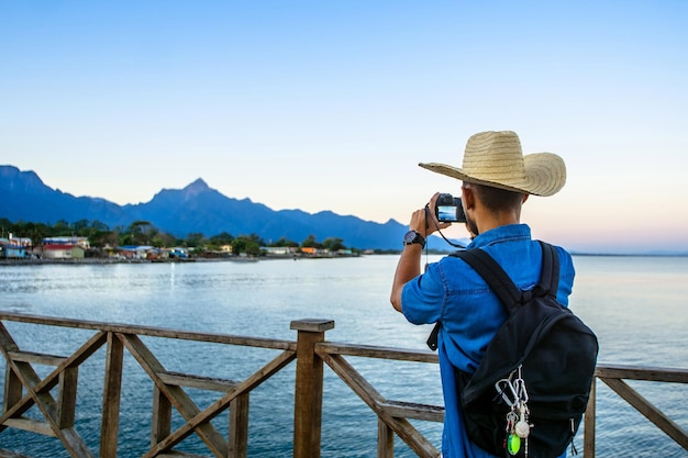 Turista tomando una foto al amanecer de las montañas y el mar en la ciudad de La Ceiba, Honduras.