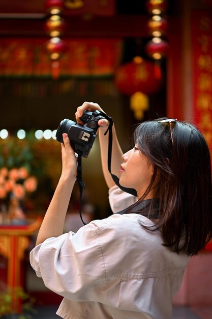 Una turista tomando fotos de un hermoso templo chino con su cámara