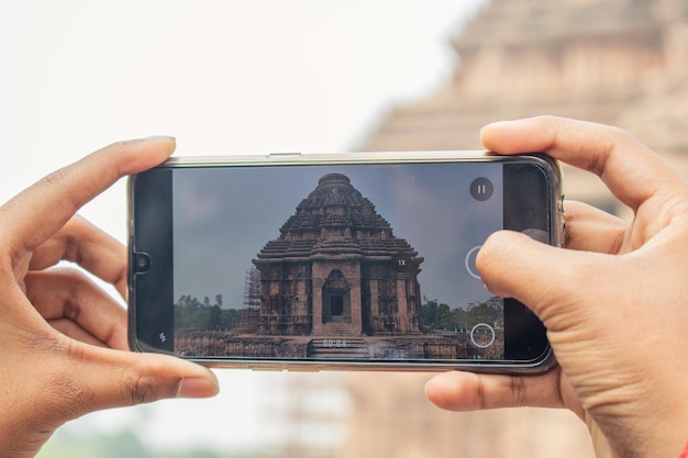 Foto turista tomando fotos con el móvil en konark sun temple, lugar de turismo indio
