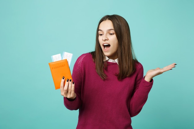 Una turista viajera con ropa informal tiene un billete de pasaporte aislado en un retrato de estudio de fondo azul. Pasajero que viaja al extranjero en escapada de fin de semana. Concepto de viaje de vuelo aéreo Espacio de copia simulado