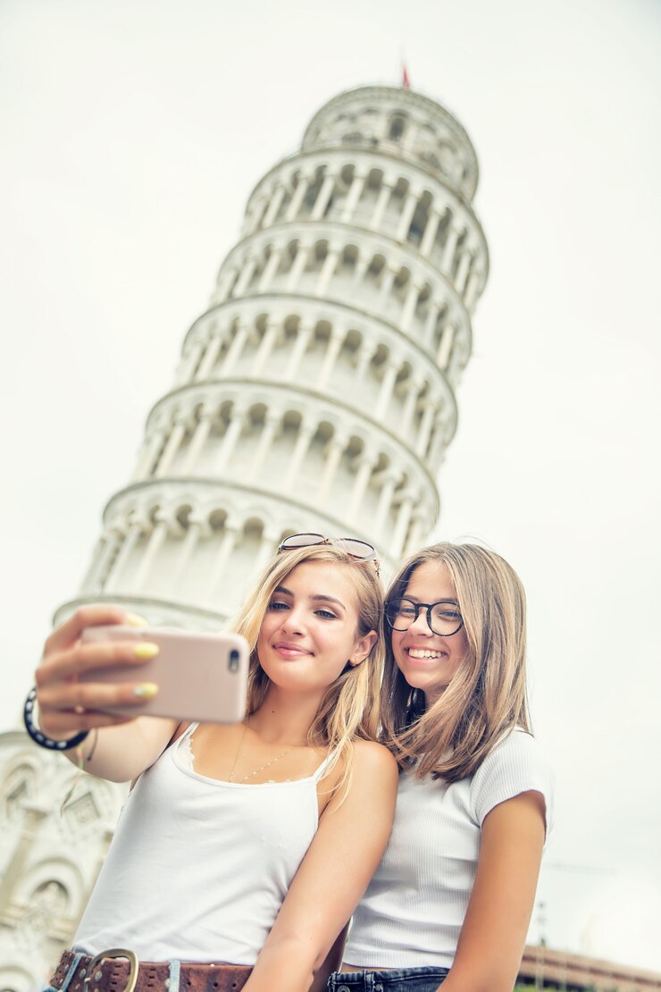 Turista de viajero de chicas adolescentes antes de selfie de torre de Pisa para foto o video de teléfono inteligente.