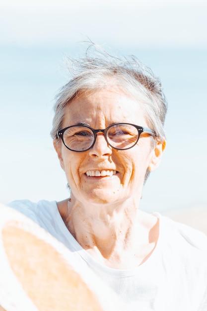 Turista viajero sonriente anciana madura dama senior mujer de 55 años de edad usan camisa blanca y un sombrero con gafas al aire libre retrato. Feliz día explorando y haciendo nuevos hábitos. Ancianos felices