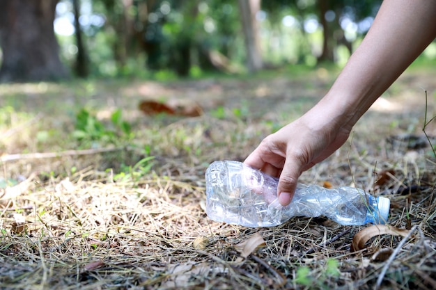 Turista voluntario mano limpiar basura y escombros de plástico en el bosque sucio gran bolsa azul