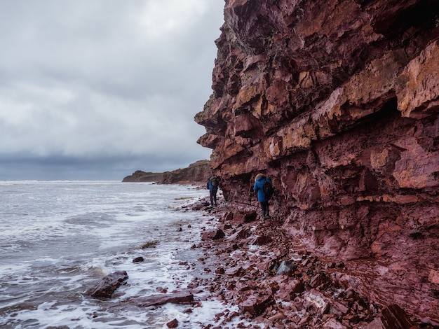 turistas en un acantilado sobre el mar con una costa estrecha.