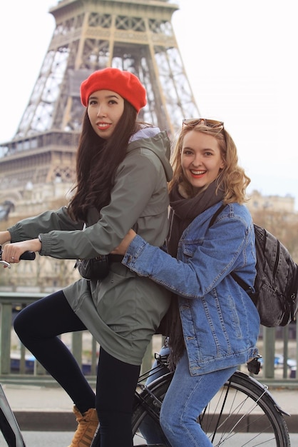 Turistas amigos chicas montando en bicicleta en el centro de París La torre Eiffel está en el fondo