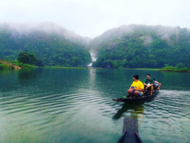 Turistas en un barco con río y cascada.