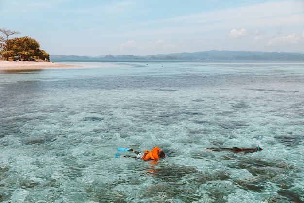 Los turistas buceando en el agua de mar transparente vistiendo chaleco salvavidas