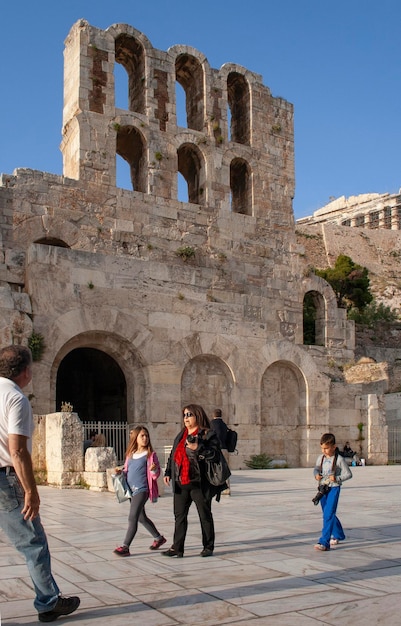 Los turistas caminan cerca del Teatro Odeon Herod en la Acrópolis en Atenas Grecia