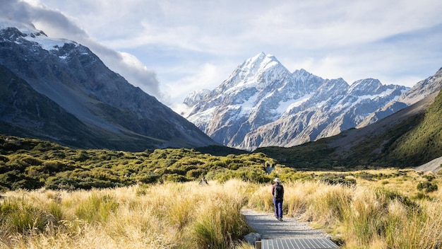 Turistas caminando por el sendero en el hermoso valle alpino con la enorme montaña nevada Mount Cook Nueva Zelanda