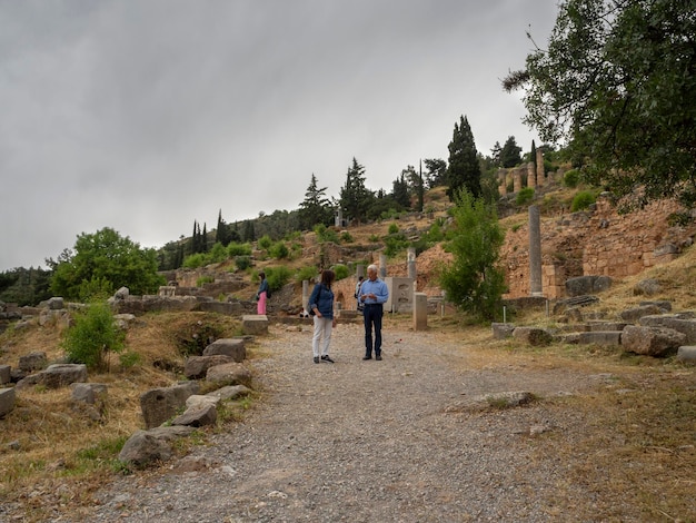 Turistas caminham pelo complexo histórico de Delphi na Grécia em um dia nublado