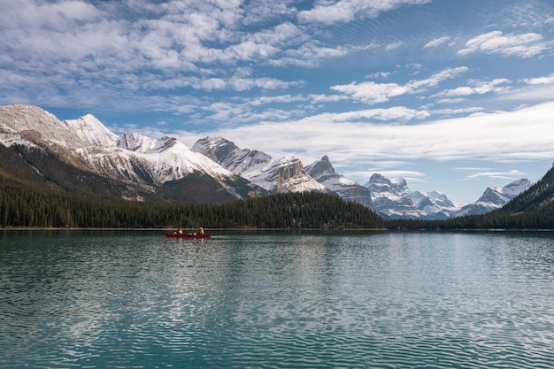 Los turistas en canoa hacia la isla Spirit con las Montañas Rocosas Canadienses en el lago Maligne en el parque nacional de Jasper, AB, Canadá