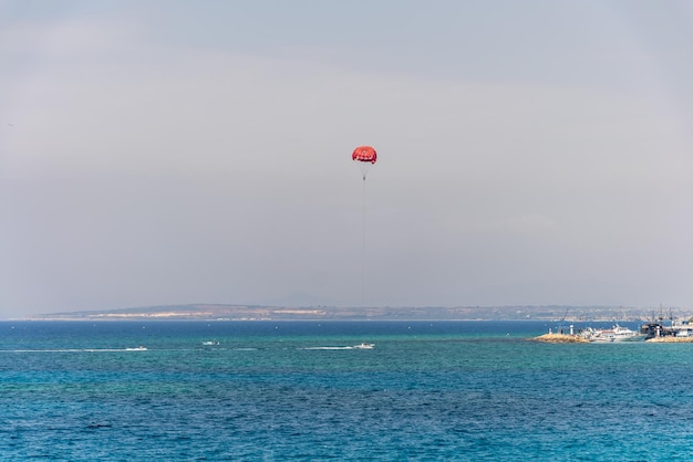 Turistas de CHIPRE AYIA NAPA se divertem em um pára-quedas sobre o mar Mediterrâneo perto do porto