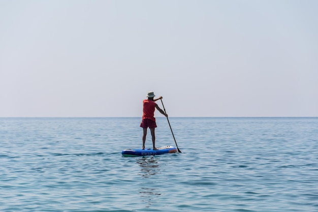 Turistas de MONTENEGRO BUDVA se dedicam a remar na prancha SUP na superfície do mar calmo