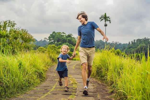 Turistas de pai e filho em campuhan ridge walk, scenic green valley em ubud bali. viajando com o conceito de crianças.