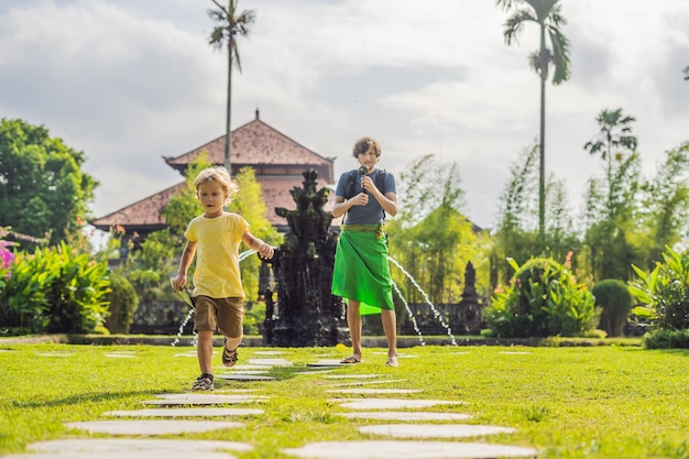 Turistas de pai e filho no templo hindu tradicional balinês Taman Ayun em Mengwi. Bali, Indonésia Viajando com o conceito de crianças