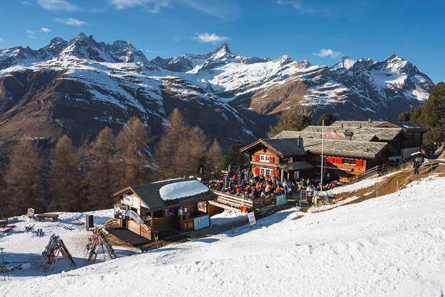Turistas do lado de fora do café na estância de esqui com belas montanhas cobertas de neve