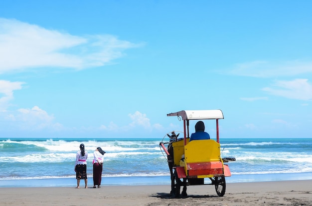 Los turistas y Dokar de pie en la orilla de la playa Parangtritis Yogyakarta Indonesia Dokar es un medio de transporte tradicional tirado por un caballo