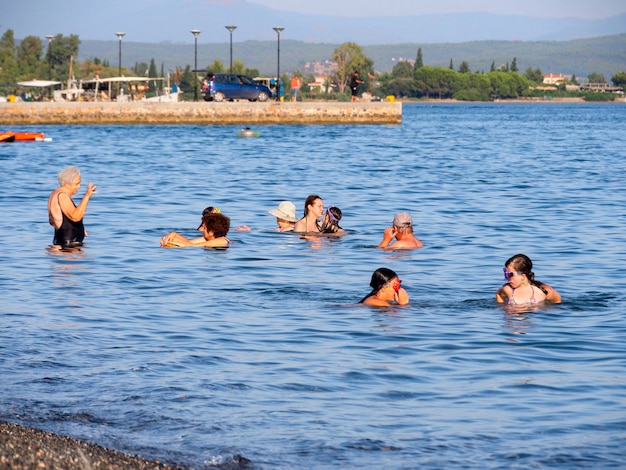 Turistas e veranistas nadam no mar Egeu e relaxam na praia em um dia de verão na Grécia