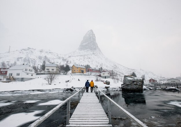 Turistas em pé na ponte de madeira com neve
