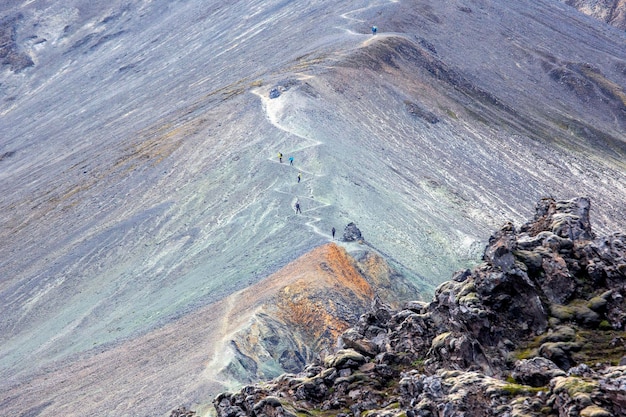 Turistas escalam a trilha até o topo do vulcão Lava vulcânica perto do vulcão em Landmannalaugar Islândia
