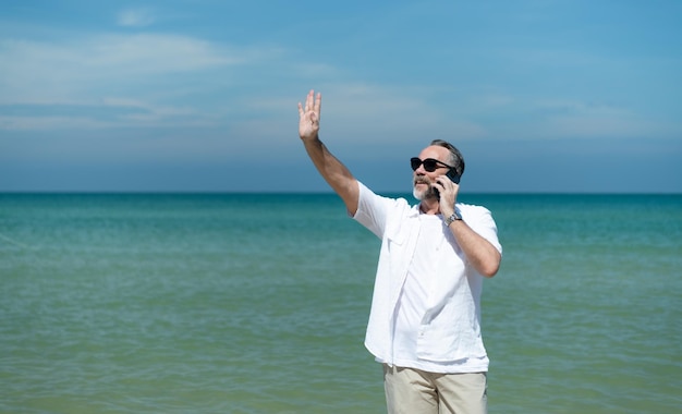 Turistas extranjeros pasean por las hermosas playas del mar azul de Asia hablando por teléfono con un amigo